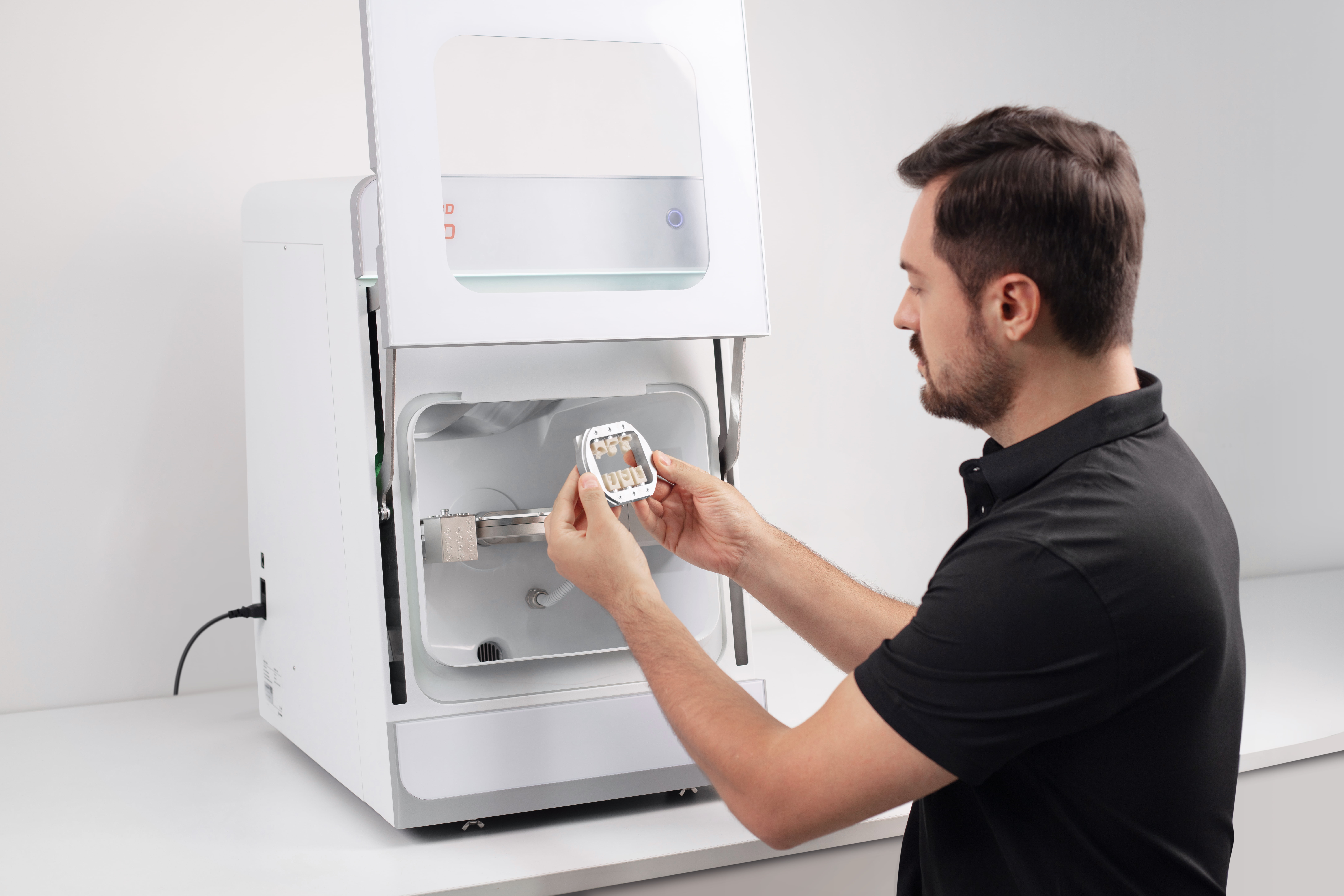 Technician inspecting restorations inside UP3D dental milling machine